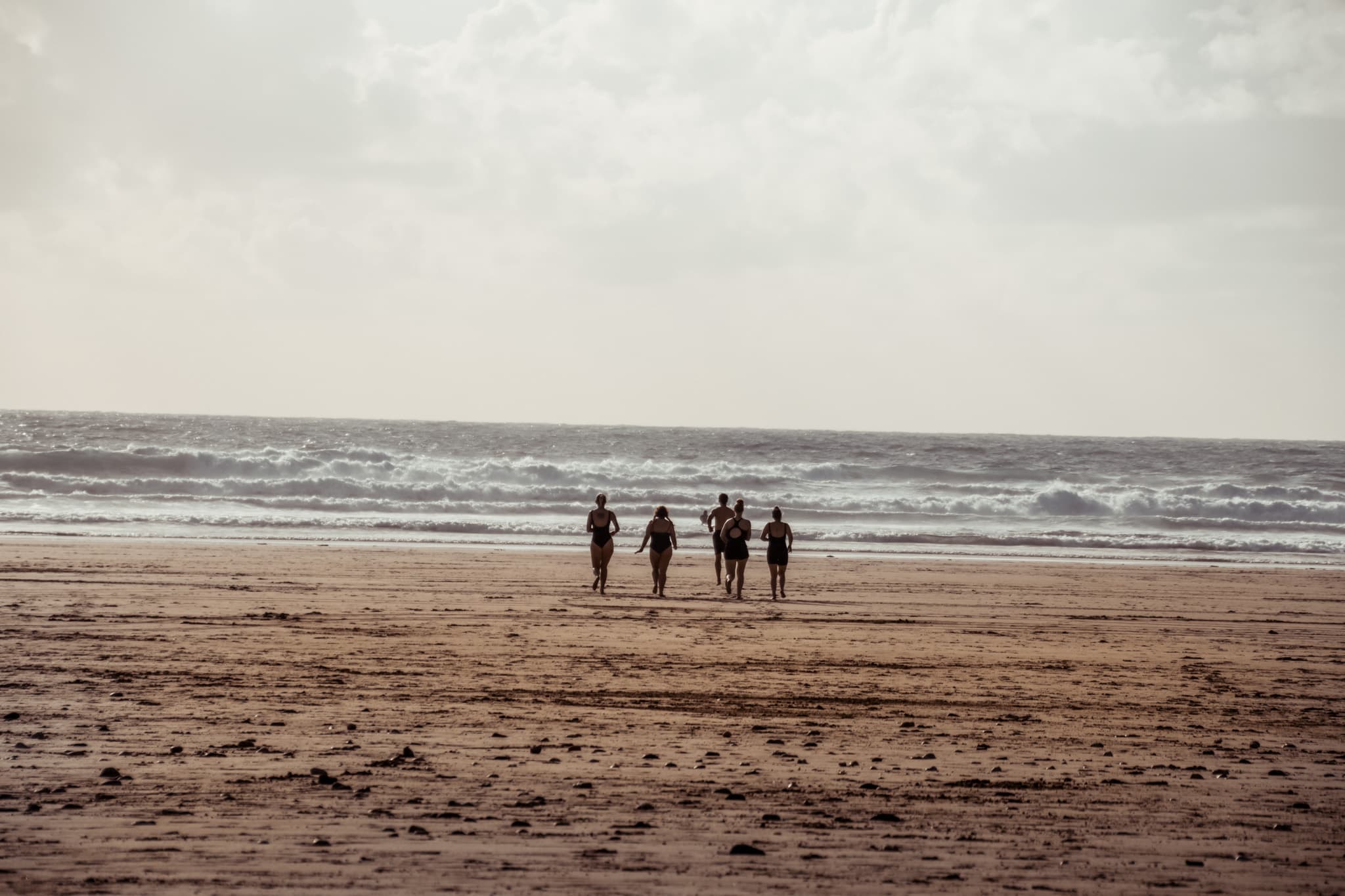 A group of sea swimmers running into the surf together