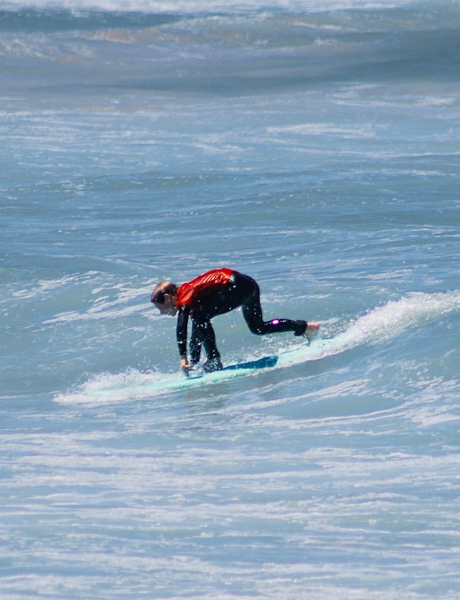 A young surfer popping up on a wave during a lesson