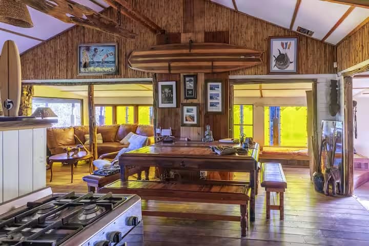The lodge's lounge, with a surfboard mounted above African art and warm timber