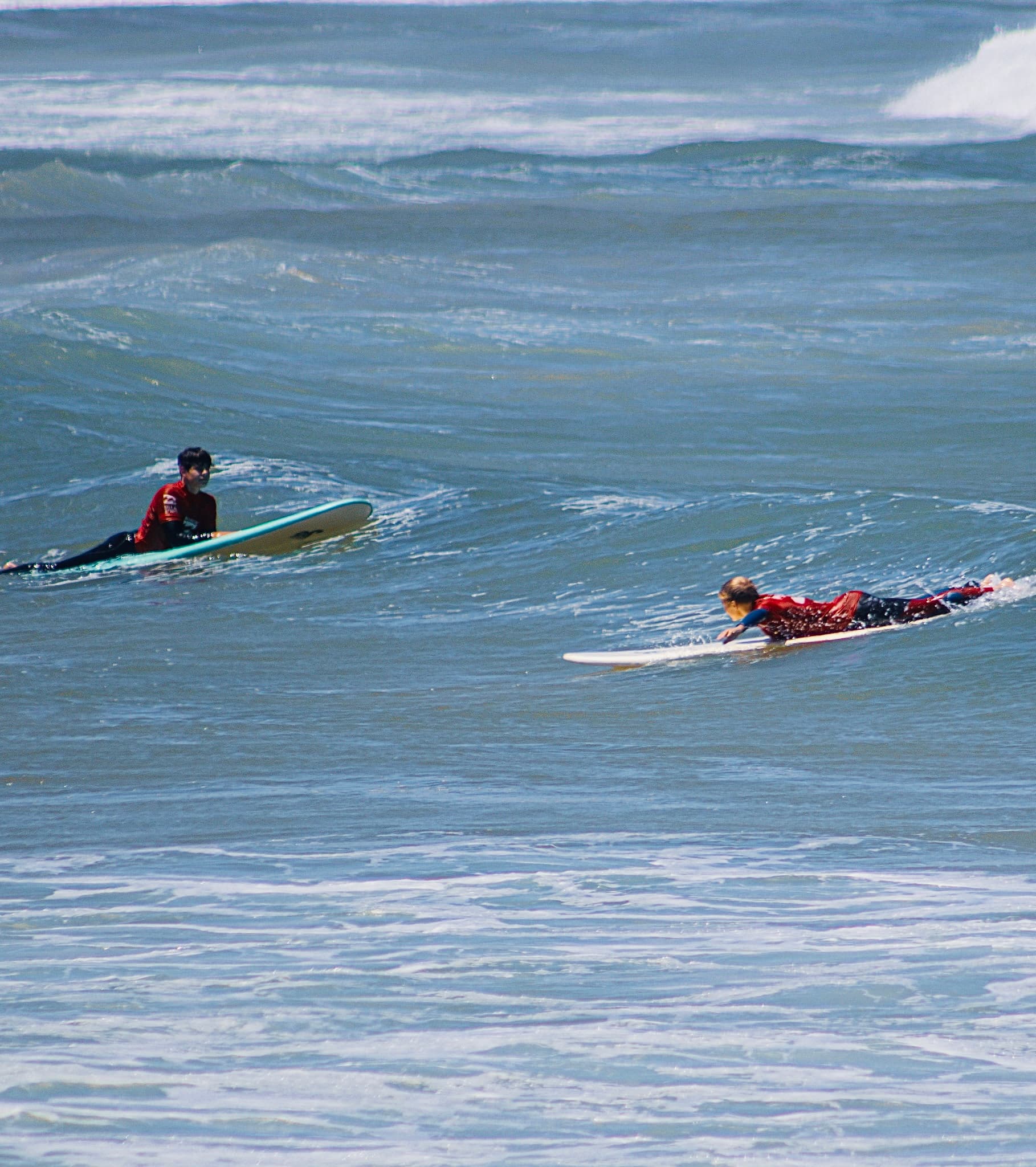 Two surfers paddling out past the breakers