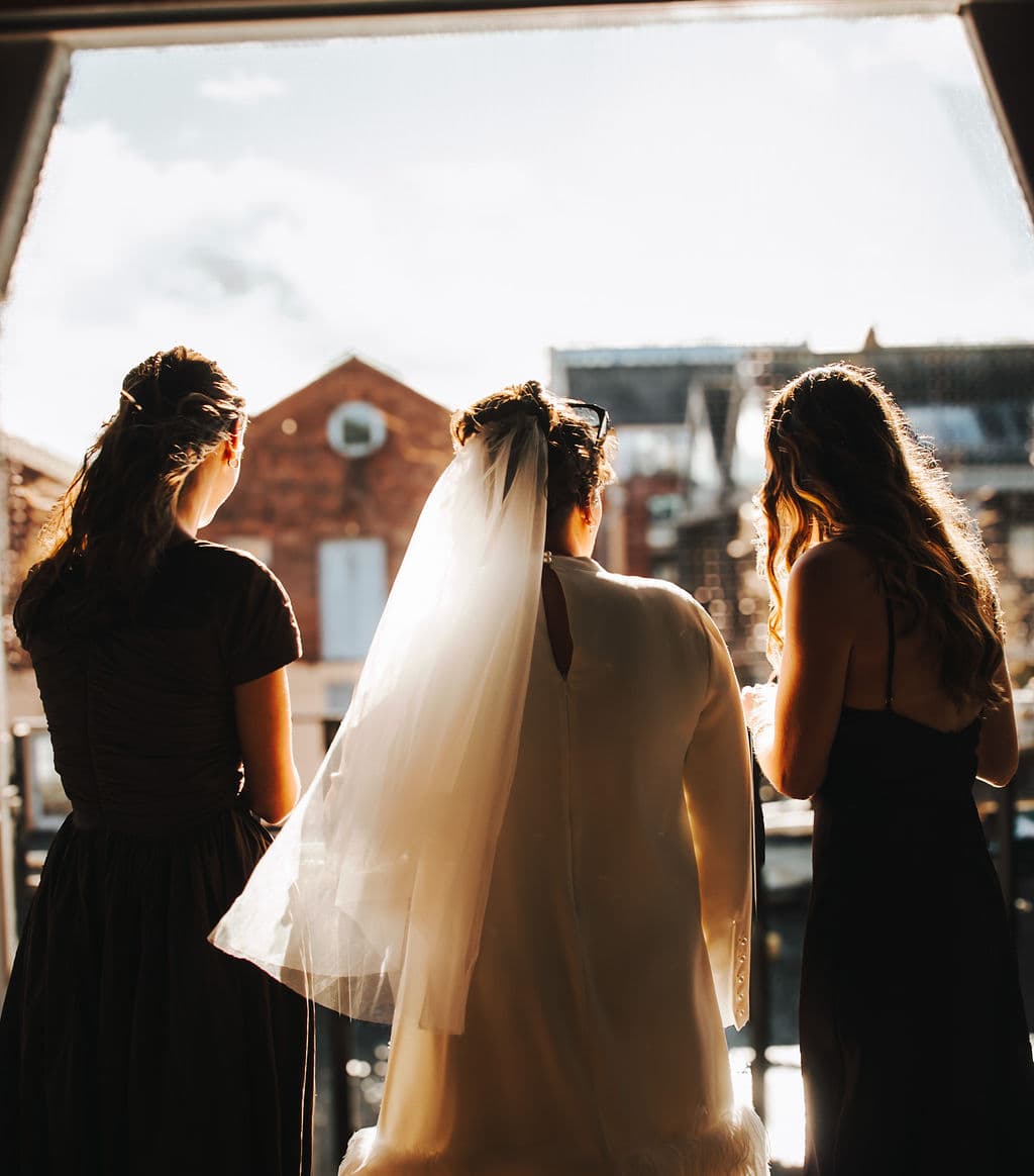 The bride and two bridesmaids, silhouetted against the evening sky