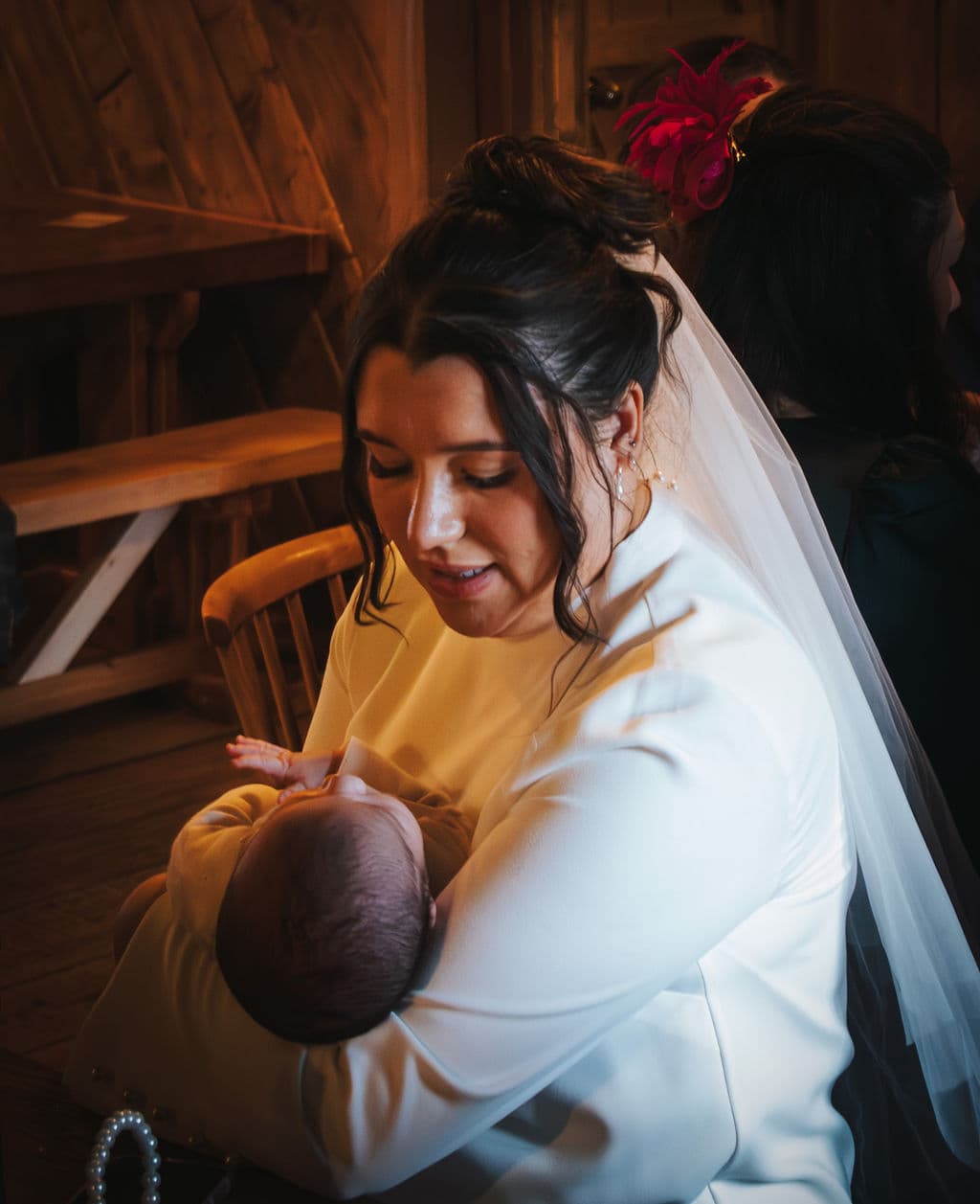 The bride holding a newborn, still in her wedding dress