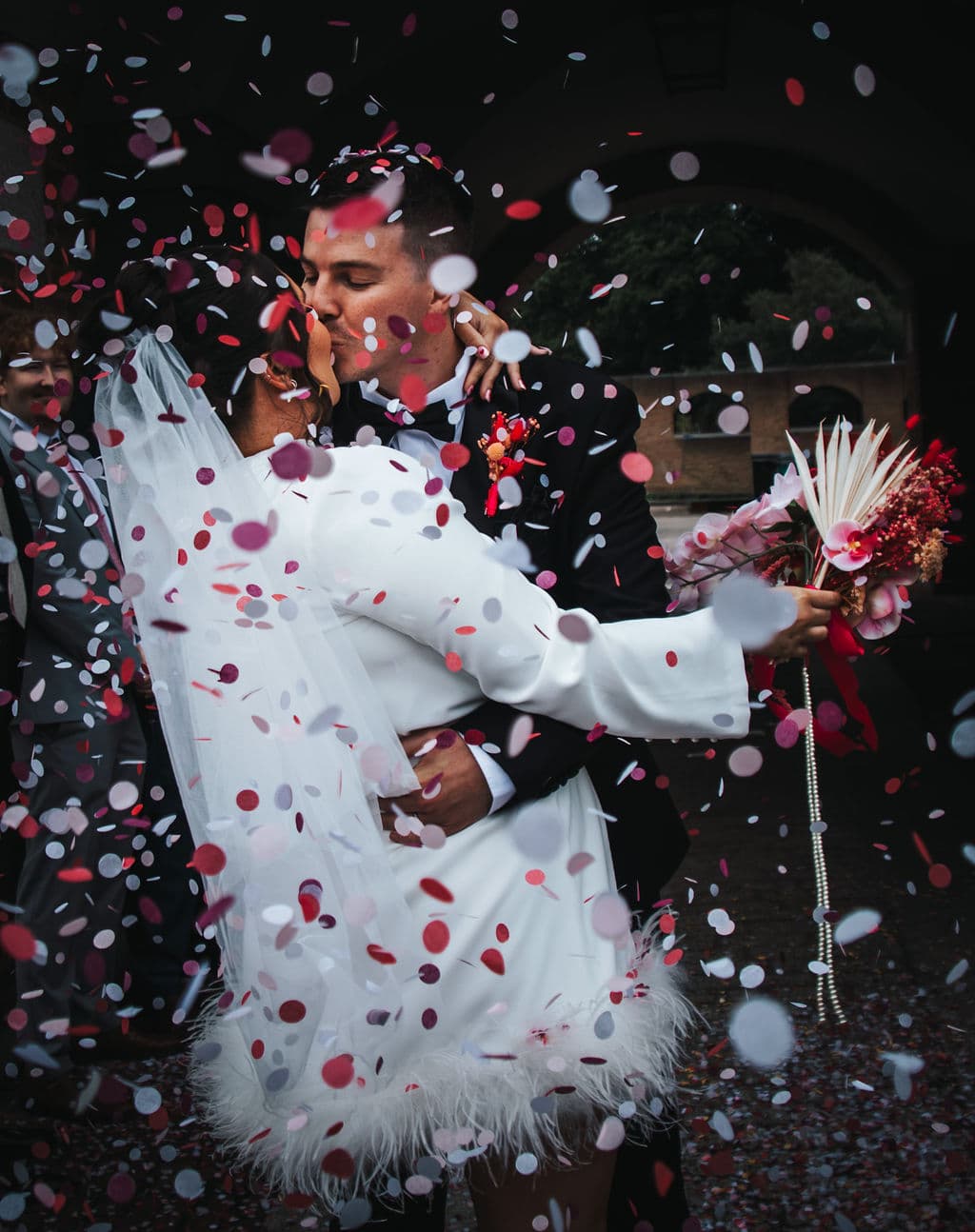 The couple kissing in a shower of confetti