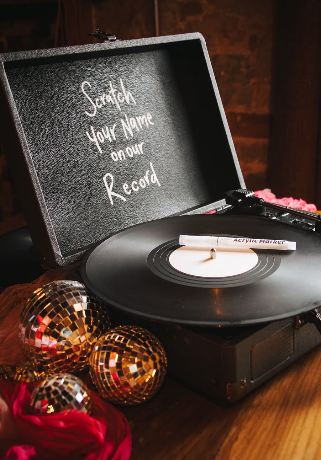 A record player set up as a wedding guest book, with a note to scratch your name onto the vinyl