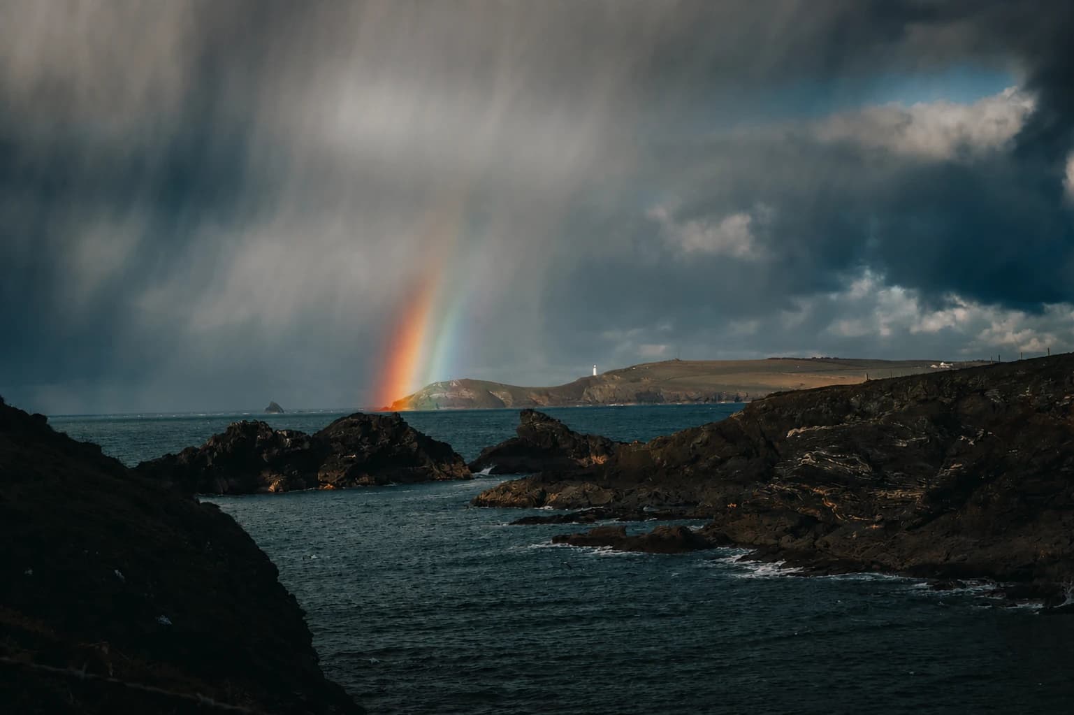 A rainbow over a headland on the coast