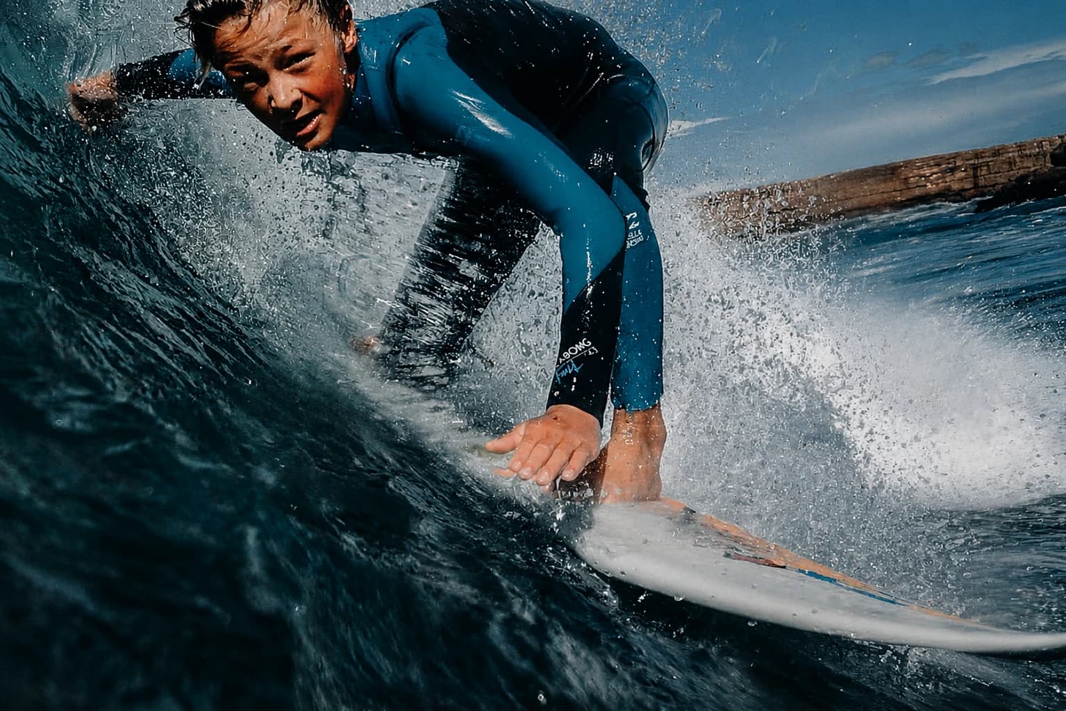 A surfer riding a wave, low angle, spray catching the light
