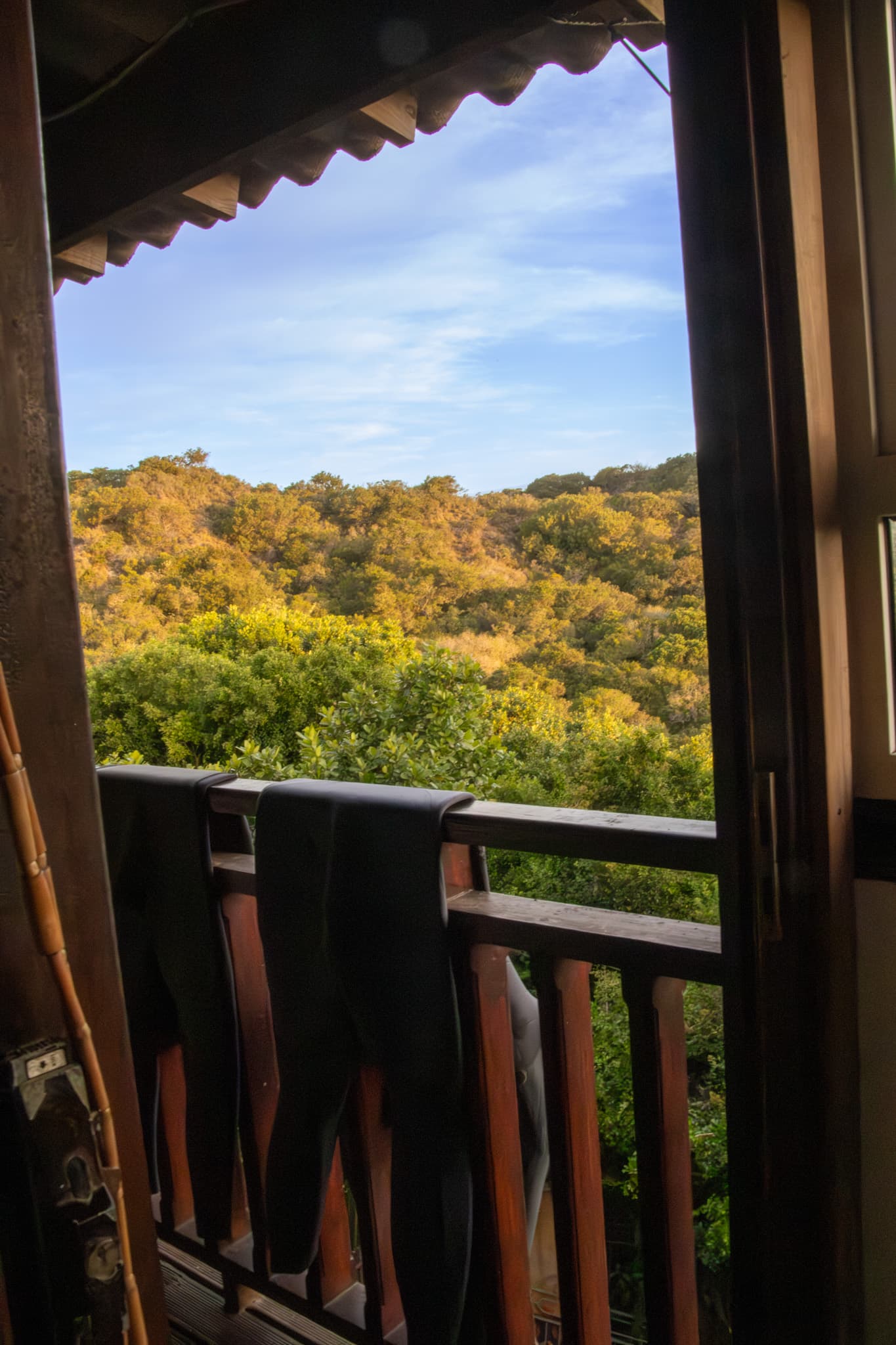 Wetsuits drying over the lodge balcony rail, looking out over the Eastern Cape hills