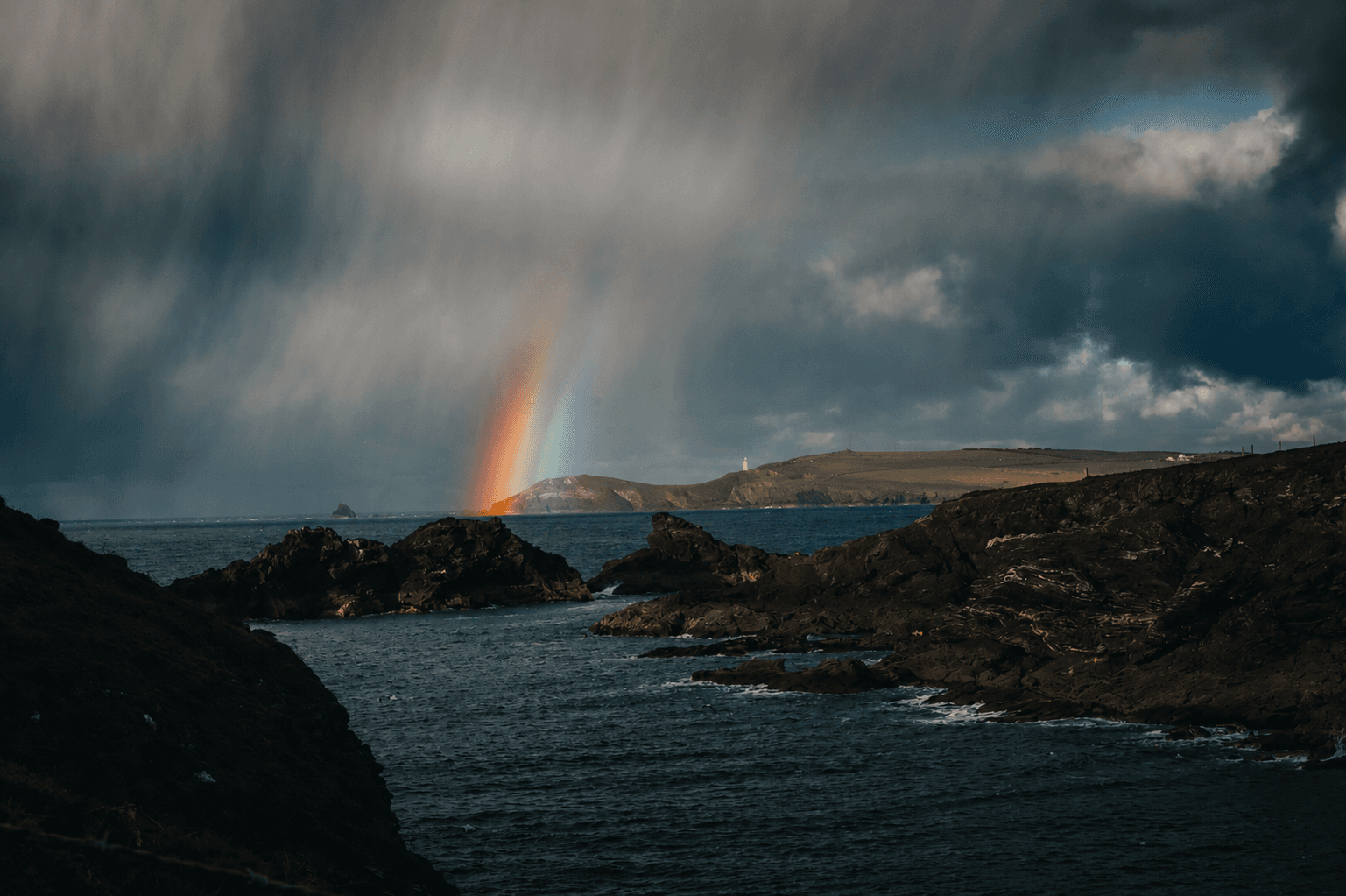 A rainbow breaking over the sea after a storm, Cornwall