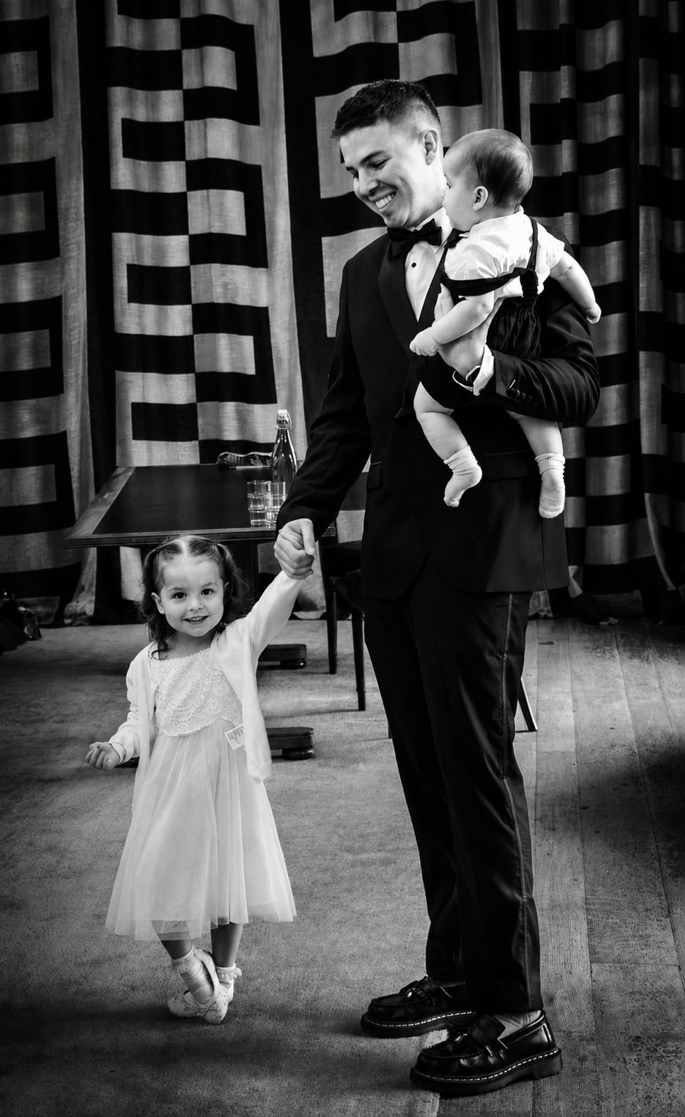 Groom holding baby, small girl dancing holding his hand, black and white