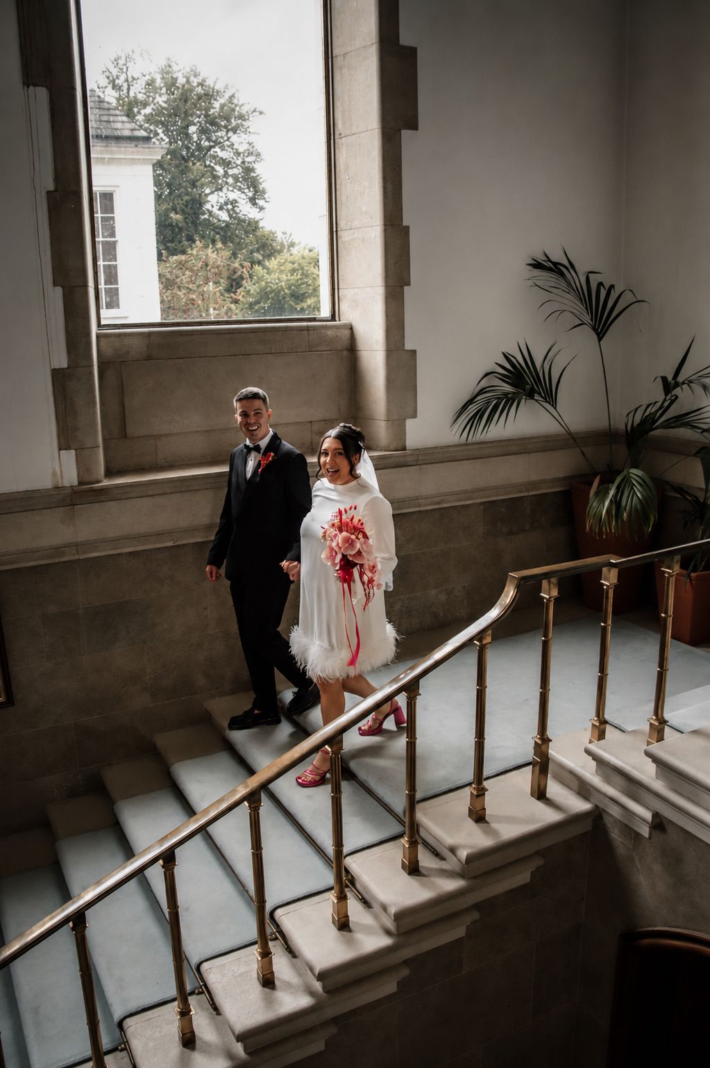 Bride and groom ascending grand staircase, colour